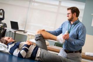 Physical therapist helps patient with knee exercises
